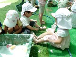 泡遊びで足に泡を塗っている子どもの写真