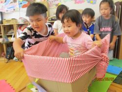 5歳児に補助されて段ボールで坂を滑り降りる写真
