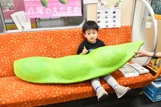 写真：大きな枝豆のオブジェと記念撮影をするこども