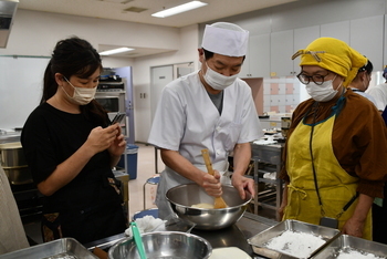 講師が大福の餡をこねるのをみつめる参加者たち