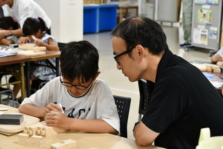 木製スツールを制作する子どもを見守る父親
