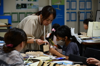 協力して木製スツールを制作する司会者と子ども