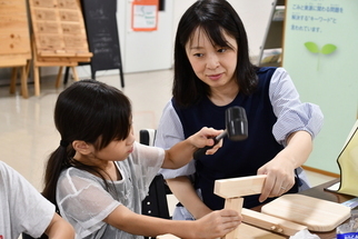 金槌を使って木製スツールを制作する子どもと保護者