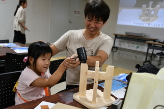 笑顔で木製スツールを作る親子