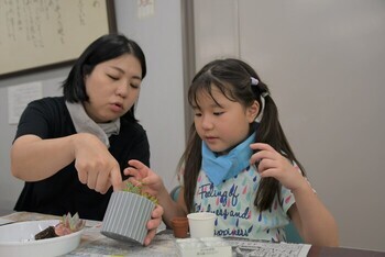 たくさんの種類の中からお気に入りの多肉植物を選び、鉢の中での配置を考える児童