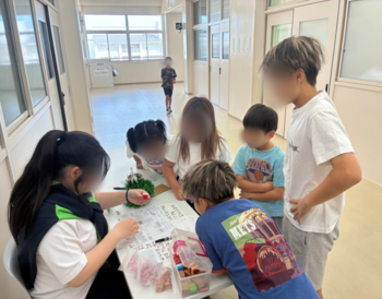 お店の説明を聞く子どもたち。低学年は前のめりになって、高学年の説明を聞いている。