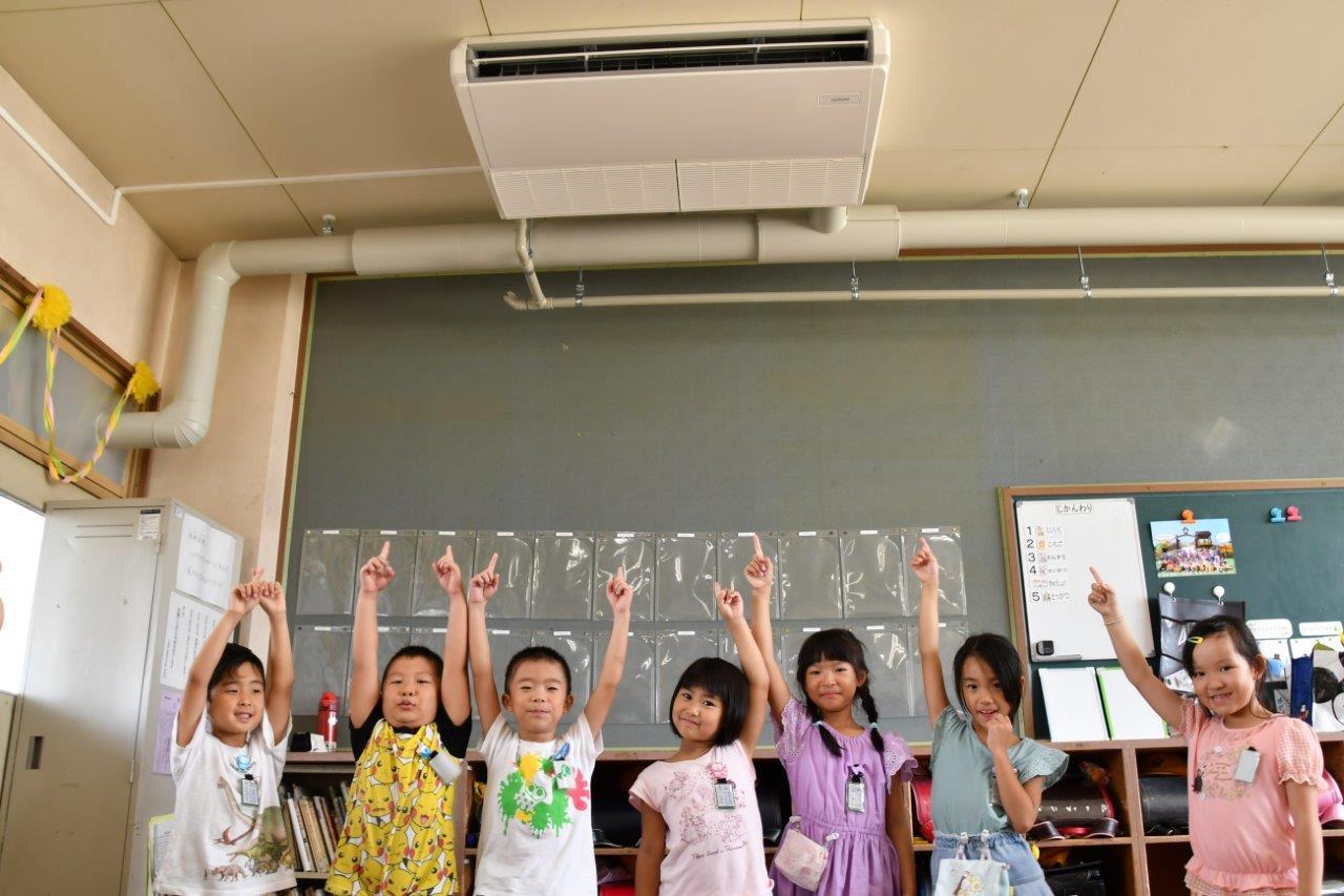 エアコンがついた小学校教室で手をあげる子どもたち