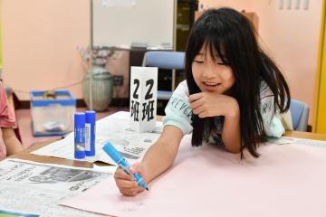 笑顔でポスターに絵を描く女子児童
